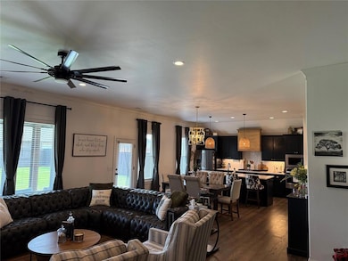 Living area featuring a chandelier, dark wood-style flooring, a ceiling fan, recessed lighting, and crown molding