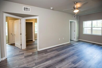 Empty room with healthy amount of natural light, dark wood-style floors, and a ceiling fan