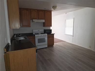 Kitchen featuring dark countertops, white range with gas stovetop, dark wood-style floors, and black microwave