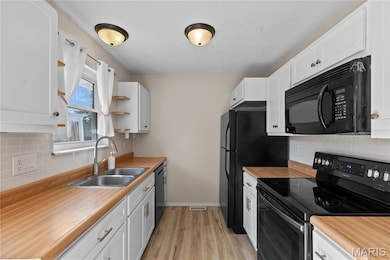 Kitchen featuring decorative backsplash, electric stove, white cabinets, and black microwave