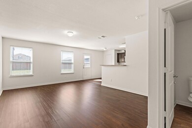 Unfurnished living room with baseboards, dark woo