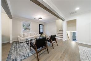 Living room with stairs, ornamental molding, light wood finished floors, and beamed ceiling