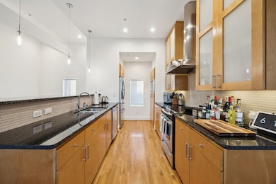 Kitchen featuring tasteful backsplash, dark stone countertops, glass insert cabinets, hanging light fixtures, and light wood-style flooring
