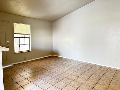 Tiled empty room featuring baseboards and a textured ceiling