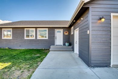 View of exterior entry with a garage, a yard, and roof with shingles