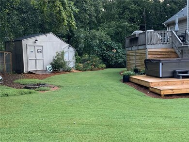 View of yard with a hot tub, a deck, and a storage