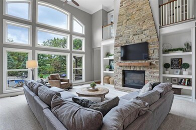 Great room has stacked stone gas fireplace, balconies and lots of natural light.