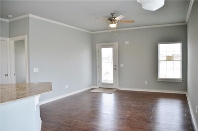 open living/kitchen area with hardwood floors, crown molding and ceiling fan.