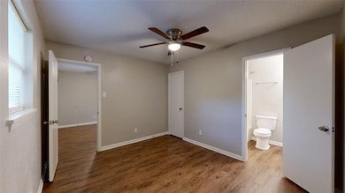 Unfurnished bedroom with dark wood-style flooring, a ceiling fan, and ensuite bath