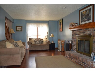 Living room with wood burning fireplace, looking f