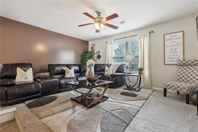 Living room featuring baseboards, a ceiling fan, v