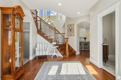 Entrance foyer with stairs, wood finished floors, recessed lighting, arched walkways, and a notable chandelier