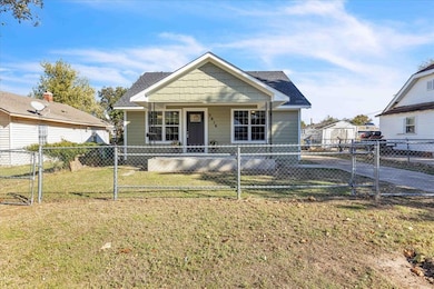 View of front facade featuring a gate, covered porch, roof with shingles, and a fenced front yard