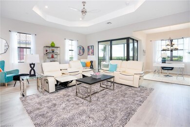 Living area featuring a tray ceiling, wood finished floors, a chandelier, and a ceiling fan