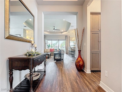 Hall with dark wood-style flooring, a tray ceiling, and recessed lighting