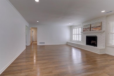 Unfurnished living room with a fireplace, wood finished floors, recessed lighting, and crown molding