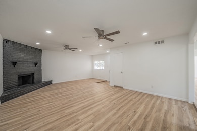 Unfurnished living room featuring light wood finished floors, ceiling fan, recessed lighting, and a fireplace