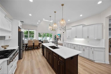 Kitchen featuring a sink, appliances with stainless steel finishes, a chandelier, a kitchen island with sink, and light wood-type flooring