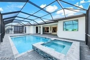 View of pool featuring a sunroom, a patio, a pool with connected hot tub, and glass enclosure