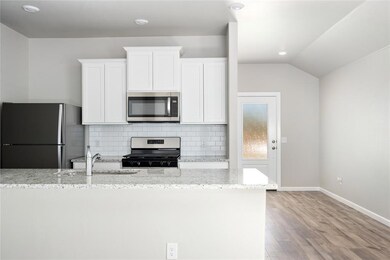 Modern kitchen with granite countertops, white shaker cabinets, and subway tile backsplash.