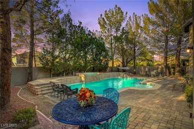 Pool at dusk with a fenced backyard, outdoor dinin