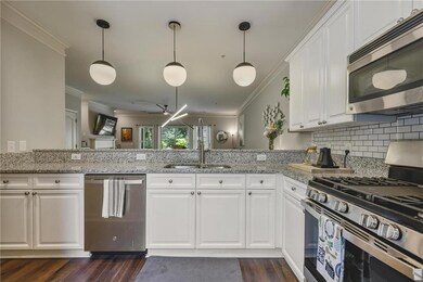Kitchen featuring appliances with stainless steel finishes, ornamental molding, tasteful backsplash, dark wood-style floors, and white cabinets