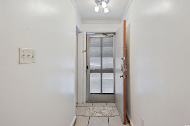 Doorway featuring light tile patterned floors, baseboards, and crown molding