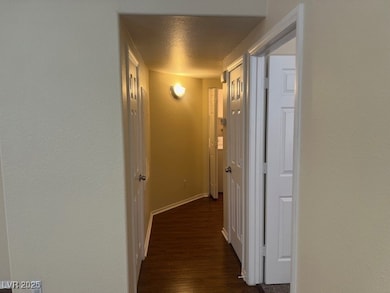 Hallway with a textured wall, dark wood-style flooring, and a textured ceiling
