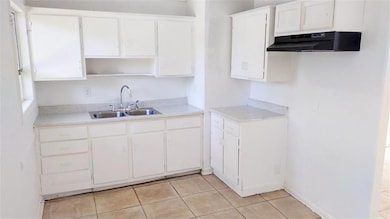 Kitchen featuring white cabinetry, sink, and light