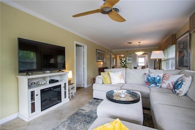 Tiled living room featuring ceiling fan and crown molding