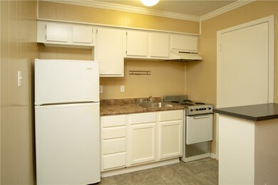 Kitchen with white appliances, crown molding, unde