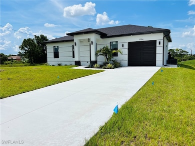 View of front of property featuring an attached garage, a front lawn, concrete driveway, and stucco siding