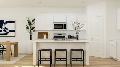 Kitchen featuring white cabinets, tasteful backsplash, light wood-type flooring, and stainless steel appliances