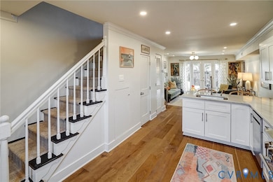 Kitchen featuring open floor plan, a peninsula, light stone countertops, white cabinetry, and recessed lighting