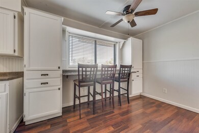 Dining space with a wainscoted wall, dark wood finished floors, crown molding, and a ceiling fan