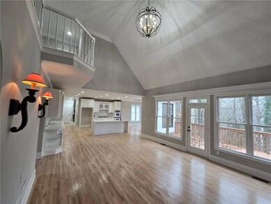 Unfurnished living room featuring high vaulted ceiling, light hardwood / wood-style floors, and an inviting chandelier