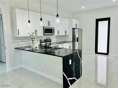 Kitchen featuring tasteful backsplash, stainless steel appliances, pendant lighting, a peninsula, and white cabinetry