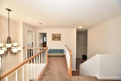 Corridor featuring an upstairs landing, ornamental molding, carpet floors, and a chandelier