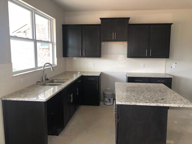 Dark cabinets with hardware, granite, and creamy subway tile backsplash. Stainless steel appliances & fridge 