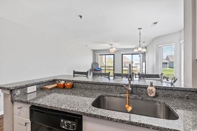 Kitchen with dishwasher, dark stone counters, pendant lighting, and a ceiling fan