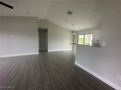 Spare room with dark wood-type flooring, a chandel