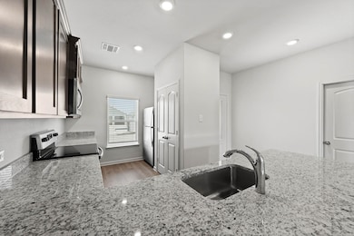 Kitchen with light stone countertops, stainless steel appliances, light wood-style flooring, and recessed lighting