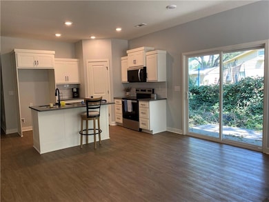 Kitchen with dark countertops, white cabinetry, electric stove, and recessed lighting