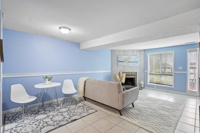Tiled living area featuring baseboards, a fireplace, and a textured ceiling
