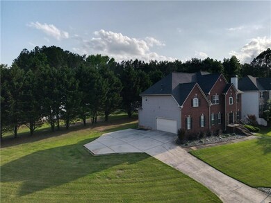 View of property exterior featuring an attached garage, a yard, driveway, and brick siding