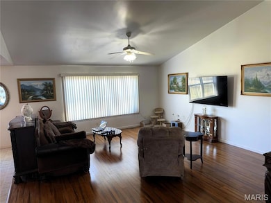 Living room with dark wood finished floors, ceiling fan, and lofted ceiling