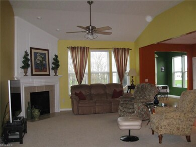 Open and bright great room with volume ceiling & neutral carpeting.