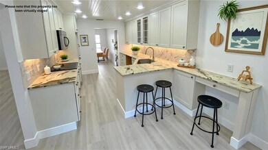 Kitchen featuring stainless steel microwave, a kitchen bar, light wood finished floors, and decorative backsplash