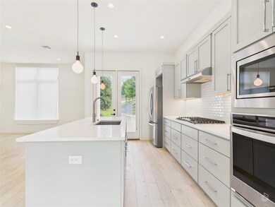 Kitchen featuring under cabinet range hood, appli