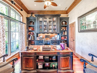 Office space featuring a textured wall, hardwood / wood-style floors, ornamental molding, a ceiling fan, and baseboards